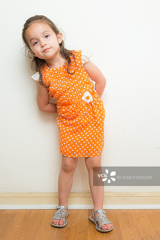 可爱的女孩看着相机，穿着橙色的裙子图片素材