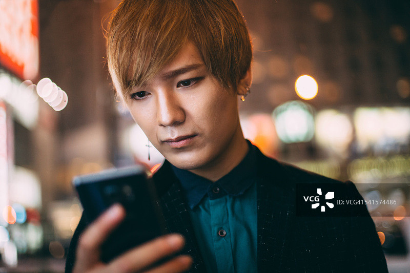 一名年轻的日本男子用手机发短信图片素材