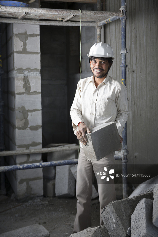 印度建筑工人拿着一块砖头。图片素材
