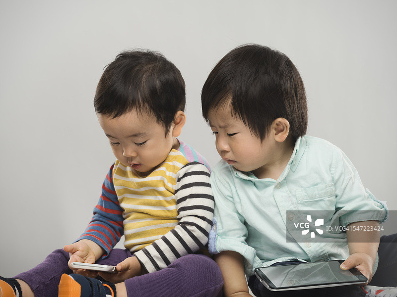 两个日本小孩和他们的电子设备的肖像。图片素材