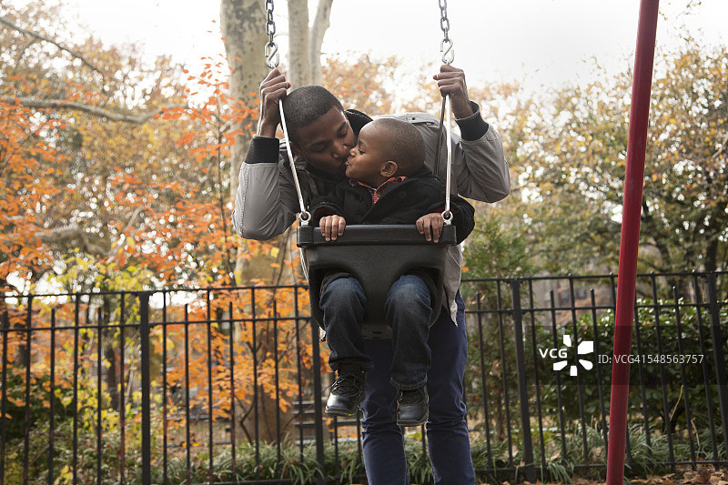 蹒跚学步的男孩和父亲在公园荡秋千图片素材