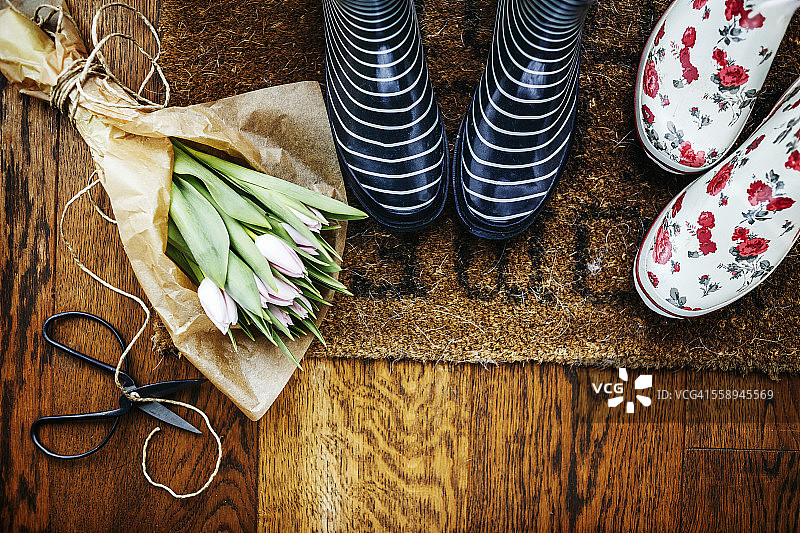 在硬木地板上的郁金香花束和剪刀的高角度视图的园艺靴图片素材