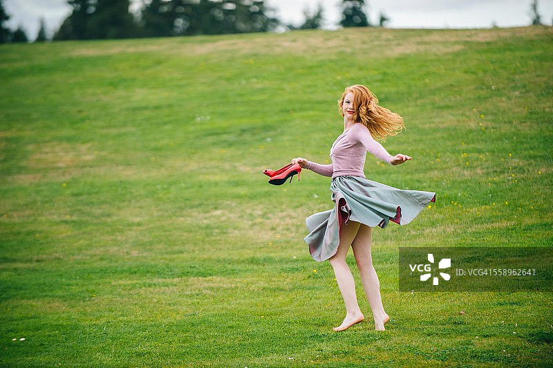一个穿着红色高跟鞋在公园跳舞的年轻女子的肖像图片素材