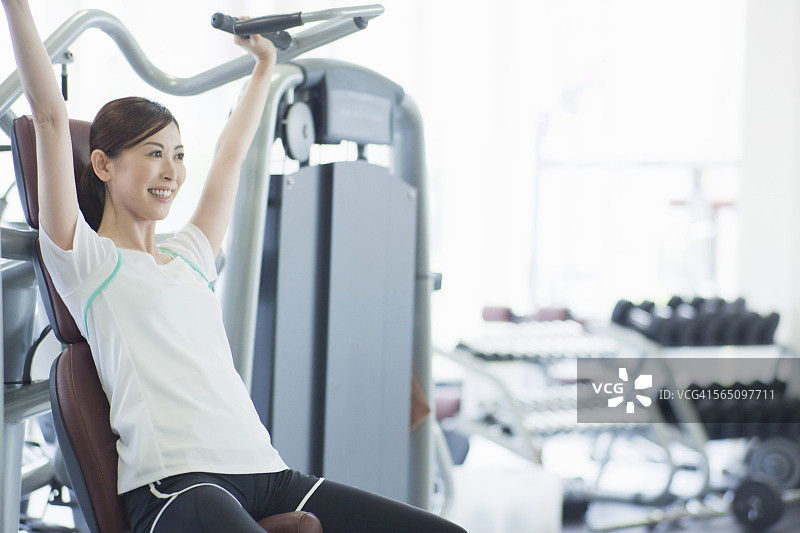 一个女人在健身房的健身机上锻炼图片素材