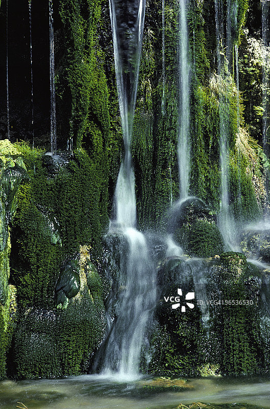 瀑布从被茂密的植物覆盖的陡峭悬崖上奔流而下。蒙大拿。图片素材