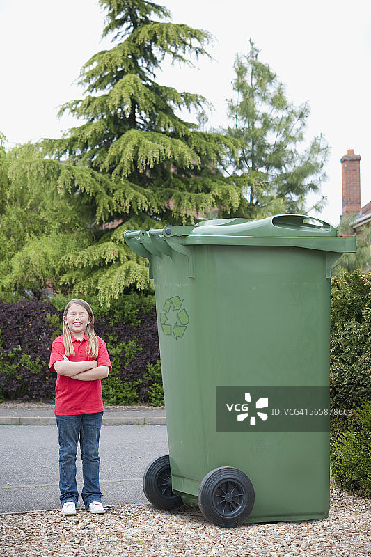 一个白人少女在大垃圾桶旁微笑图片素材