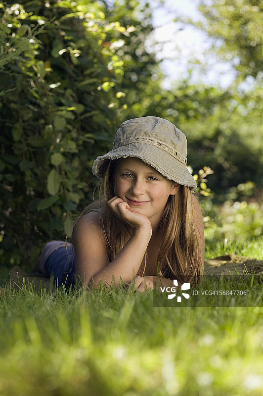 女孩(8-9)躺在草地上，手放在下巴上，肖像图片素材