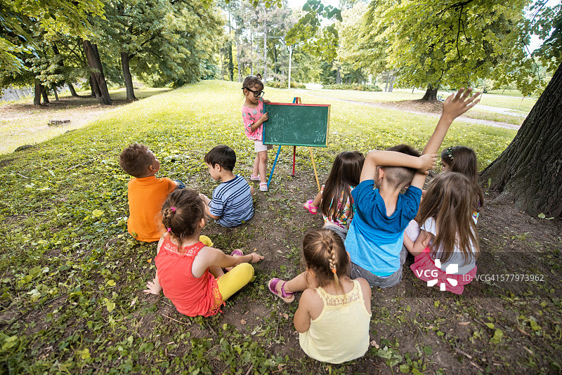 小女孩在公园里教她的朋友。图片素材