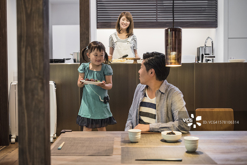 年轻的日本女孩在餐桌上拿着食物给父亲图片素材