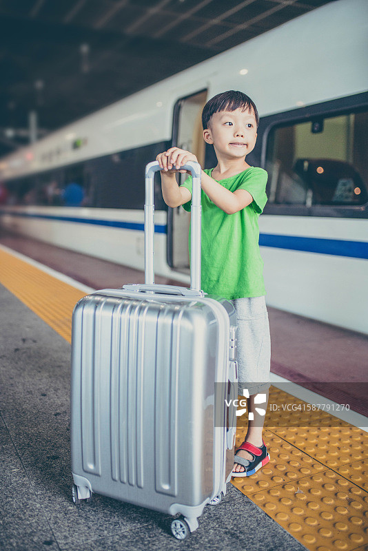 可爱的小男孩在火车站等着，孩子旅行图片素材