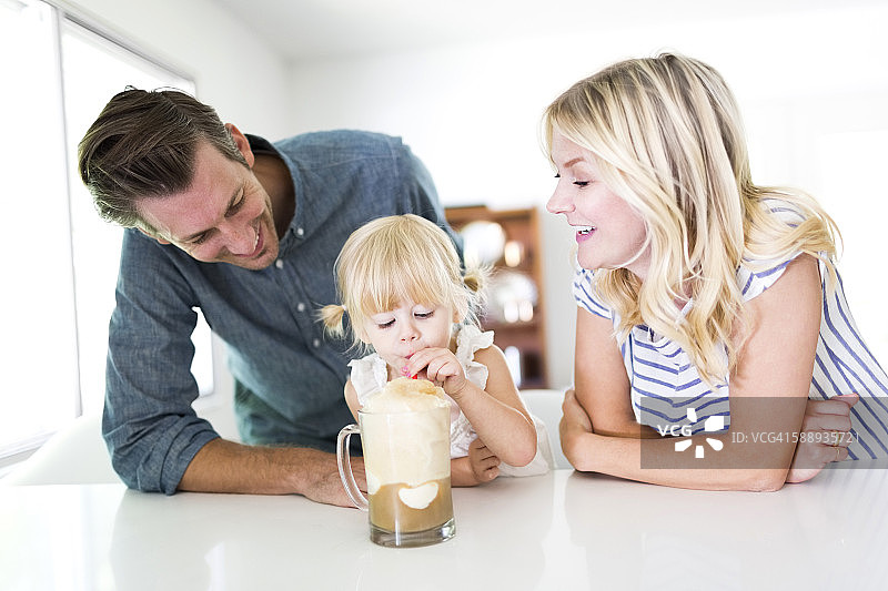 女孩(2-3)在家和父母一起喝奶昔图片素材