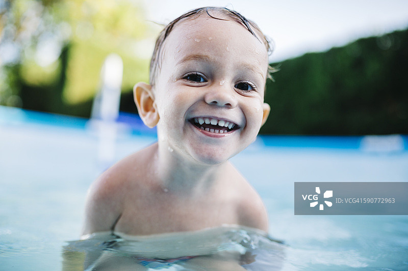 一个快乐的小男孩在嬉水池里的肖像图片素材