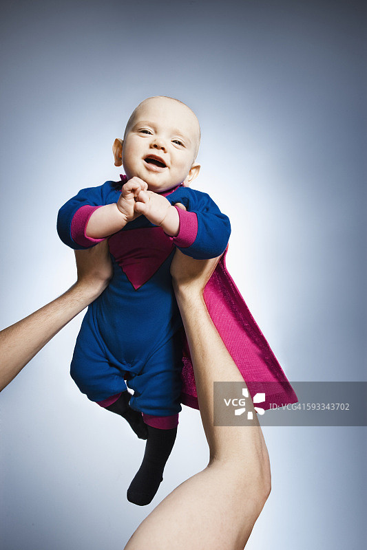 一个女人抱着穿着超人服装的婴儿图片素材