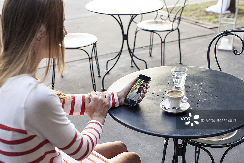 年轻女子使用多媒体智能手机在户外咖啡馆图片素材