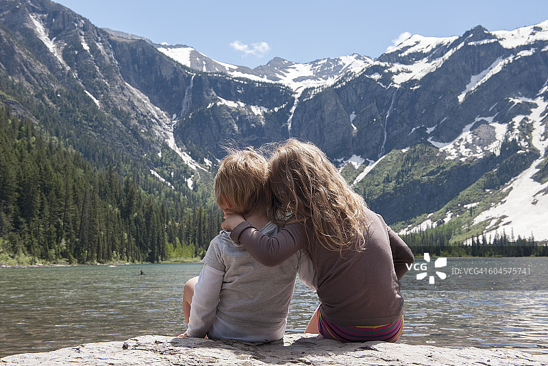 在美国蒙大拿州冰川国家公园，年幼的兄弟姐妹们正在欣赏山上的景色图片素材