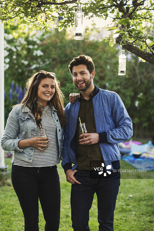 快乐的夫妇在夏季派对上拿着饮酒瓶的肖像图片素材