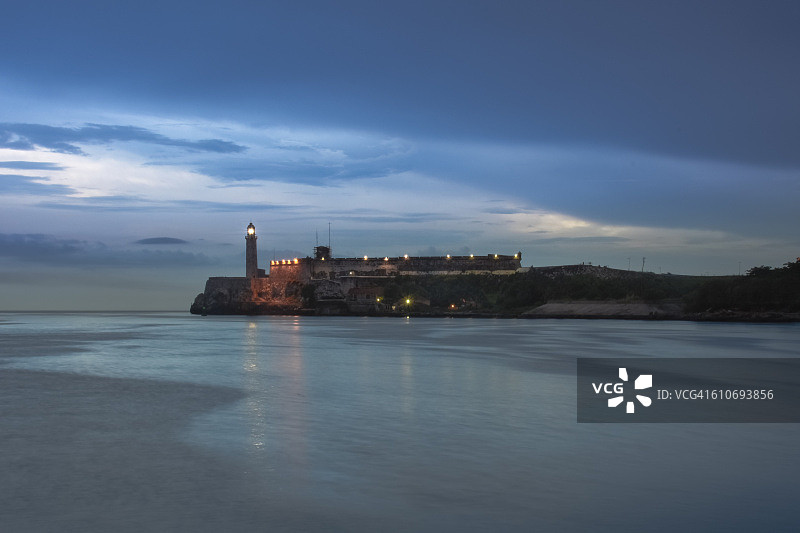 古巴哈瓦那，古老的石头灯塔和El Morro城堡在黄昏时被照亮图片素材