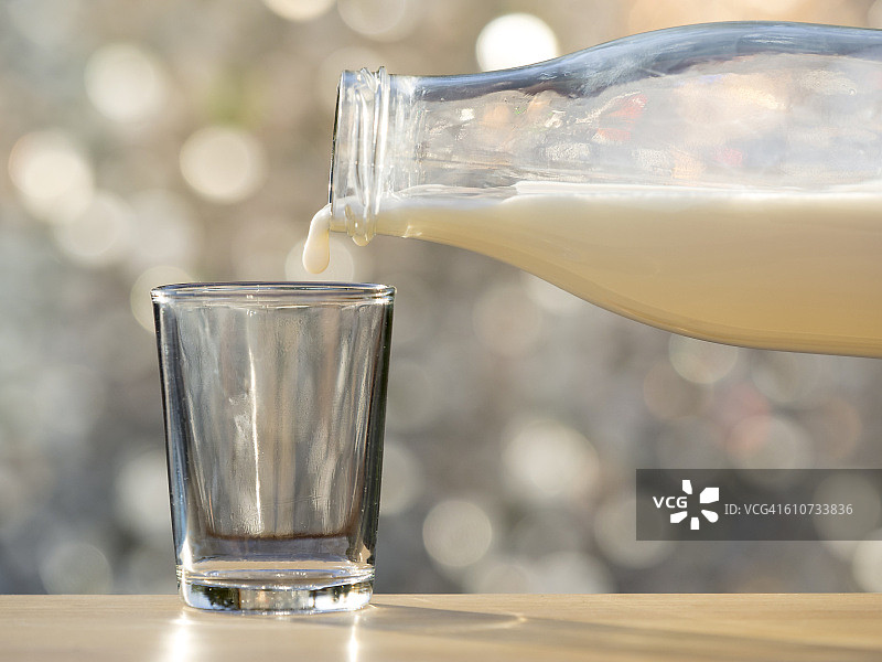 用自然光将一杯牛奶倒入玻璃杯中图片素材