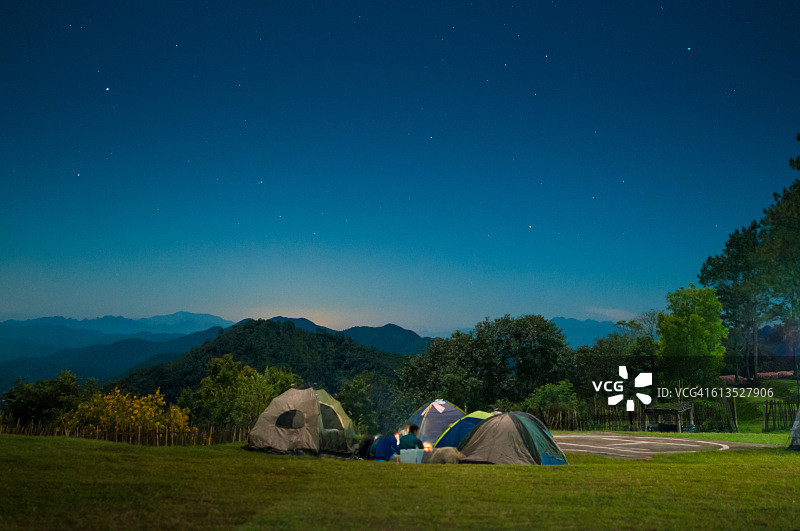 露营帐篷在繁星点点的夜空下闪闪发光。图片素材