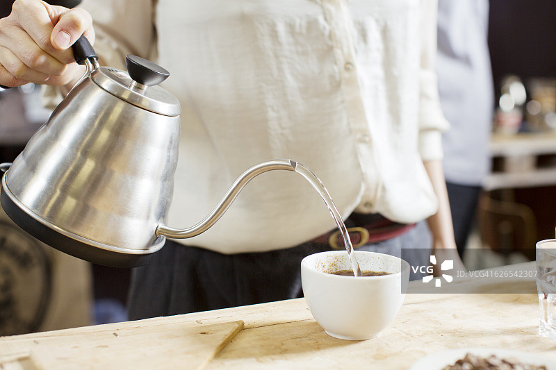 咖啡品尝员将热水倒入咖啡杯中图片素材
