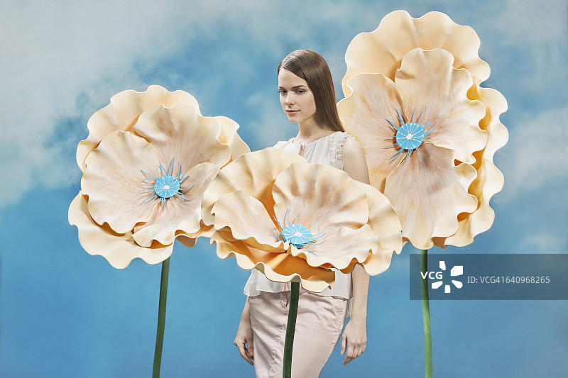 体贴的美丽女人站在花中，映衬着天空图片素材