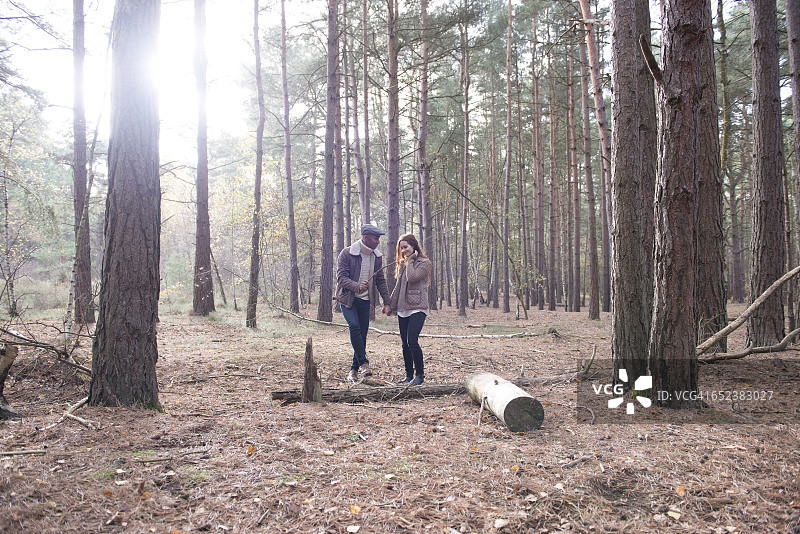 一对年轻夫妇在秋天的森林里散步图片素材