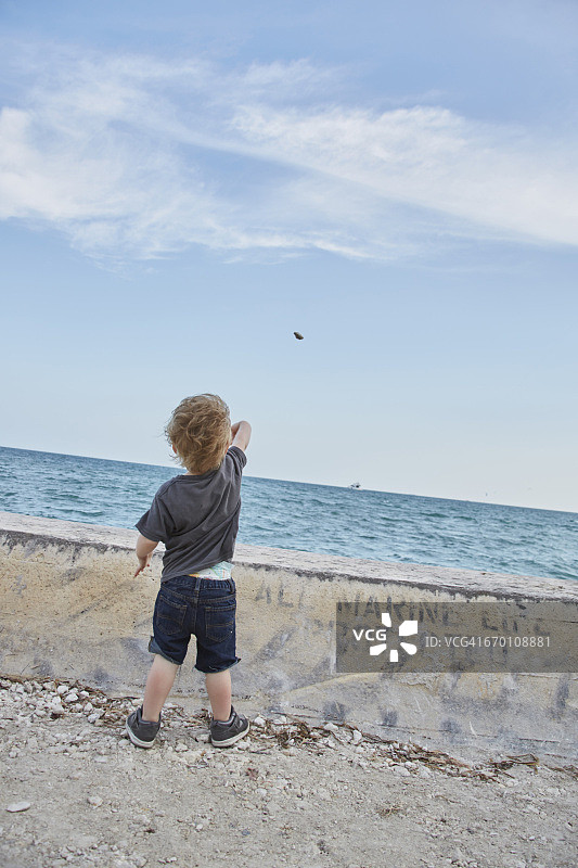 男孩往海里扔石头图片素材