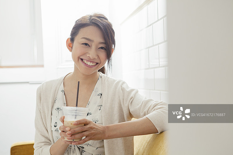 年轻女子微笑着喝着冰咖啡图片素材
