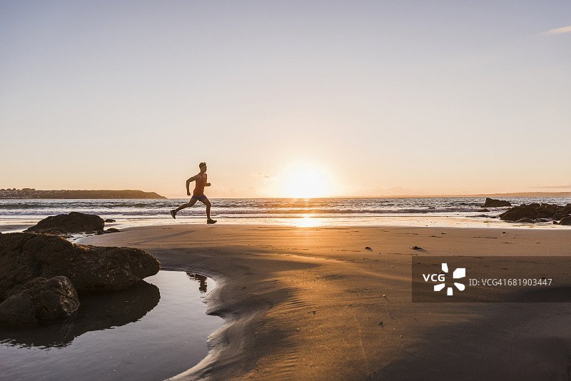 法国，克罗松半岛，日落时海滩上的慢跑者图片素材