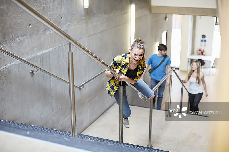 一名女学生从高教学院的楼梯扶手上滑下图片素材