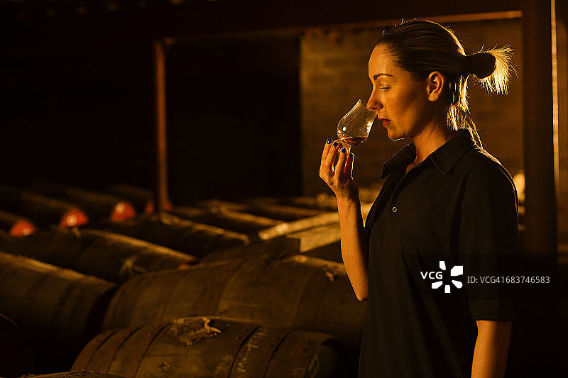 女品酒师在威士忌酒厂用玻璃杯闻威士忌图片素材