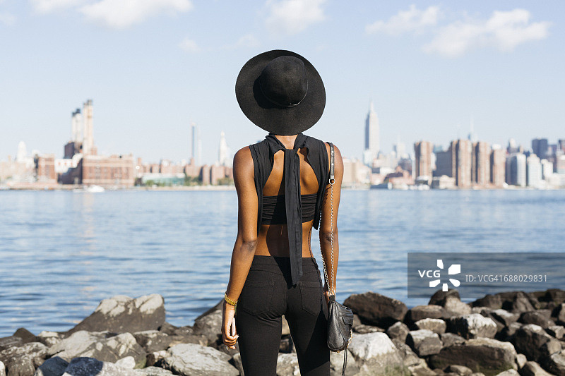 美国，纽约，布鲁克林，年轻女子站在东河图片素材