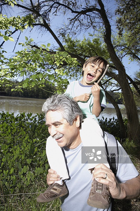 西班牙祖父在户外把孙子抱在肩上图片素材