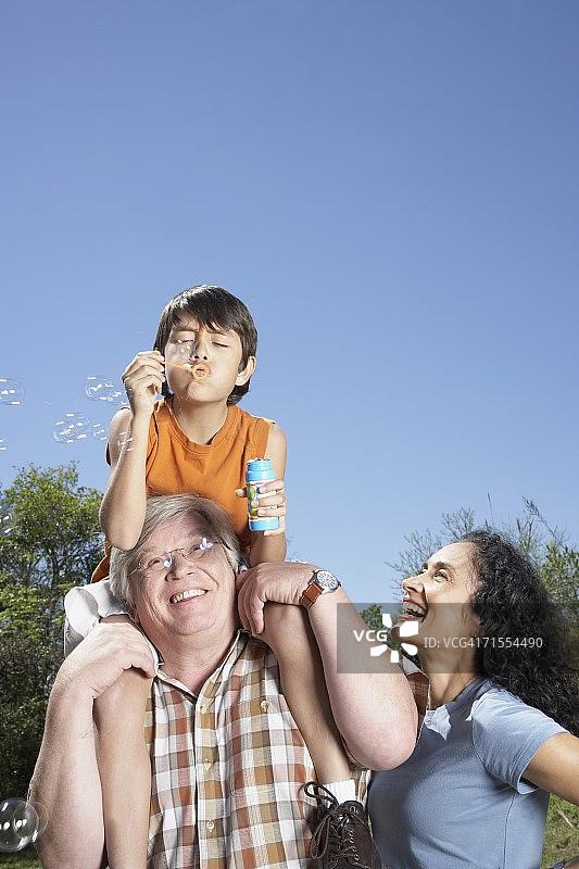 西班牙祖父母和孙子在户外吹泡泡图片素材