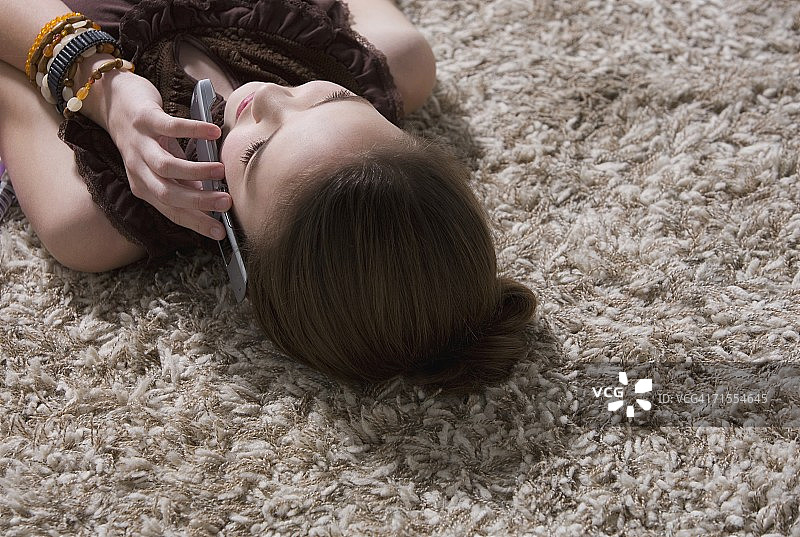 年轻女孩躺在地板上打电话图片素材