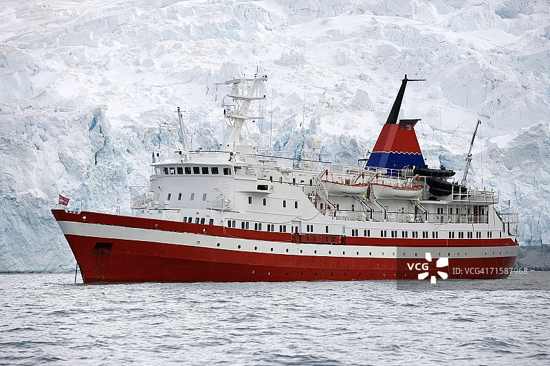 侧视图的M/S Explorer在锚与一个冰山在背景图片素材