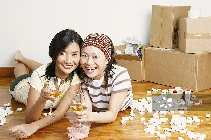 两个年轻女人的肖像躺在地板上，手里拿着几杯威士忌图片素材