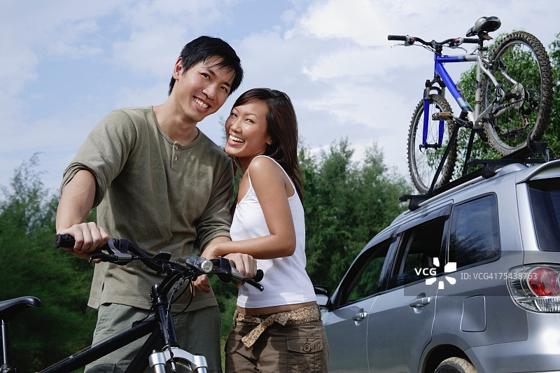男人骑着自行车，女人站在他旁边，看着摄像机图片素材