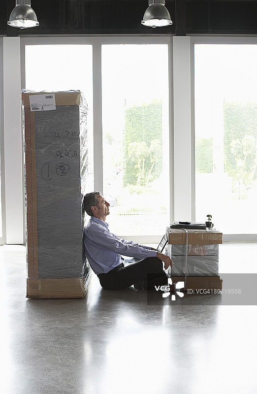 工作过度的商人坐在两个包裹之间图片素材