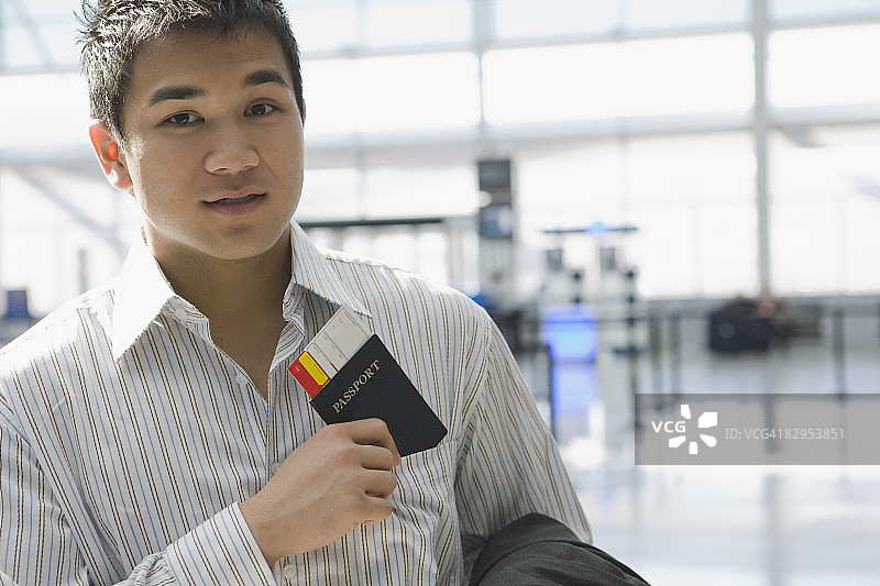 一个年轻人把护照和机票放在衬衫口袋里的肖像图片素材