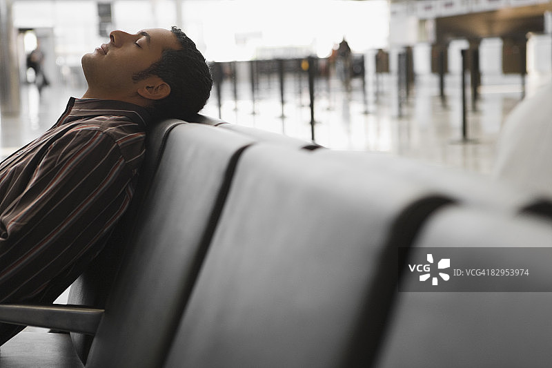 一个商人斜倚在机场的长椅上图片素材