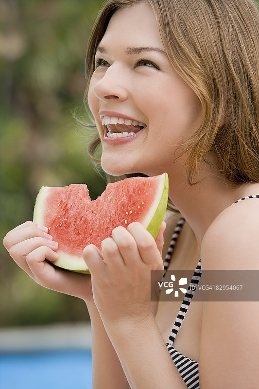一个年轻女子吃西瓜和微笑的特写图片素材