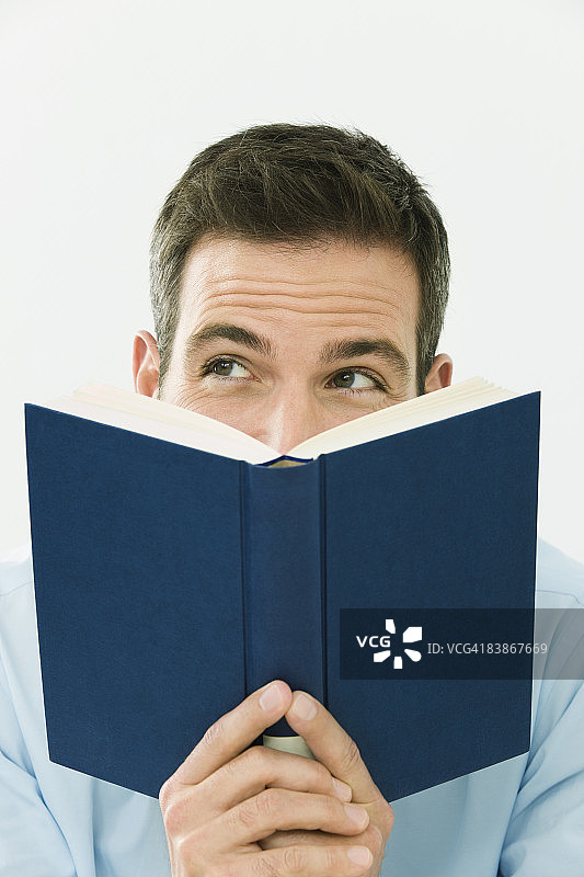 男人拿着打开的书，微笑着，望向一边图片素材
