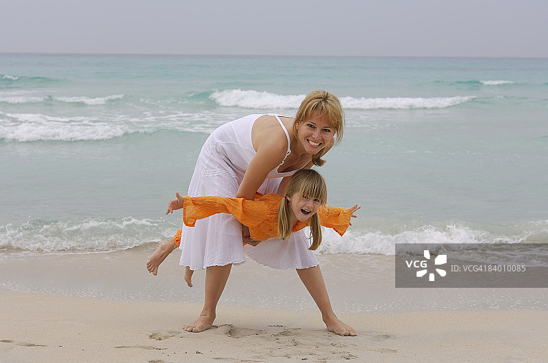 母亲(25-30岁)和孩子(5岁)在海滩玩。图片素材