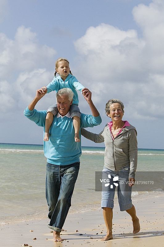 爷爷奶奶背着小女孩在海滩上散步图片素材