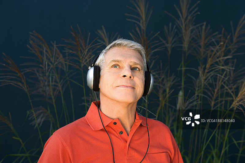 一个穿着红衬衫戴着耳机听音乐的成熟男子的大头照图片素材