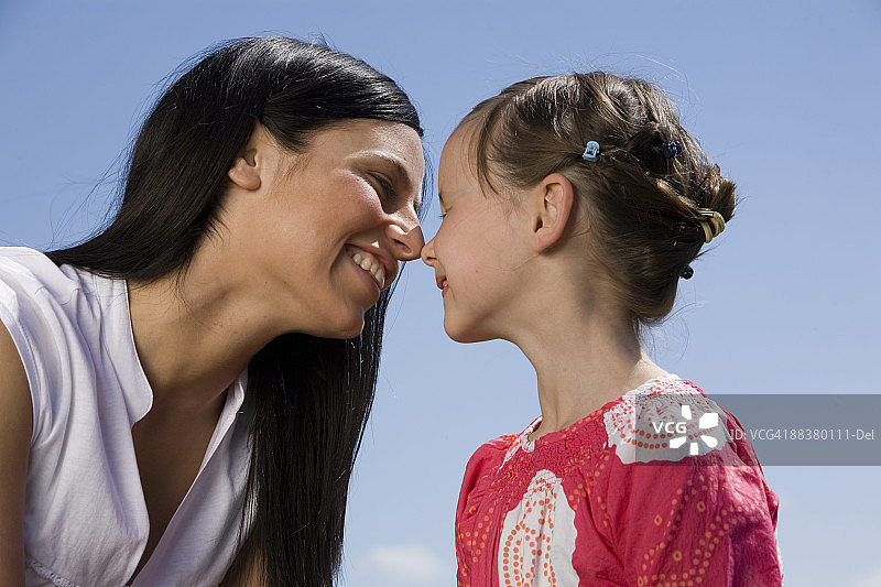 母亲和女儿(6-7岁)，鼻子对鼻子，靠近图片素材