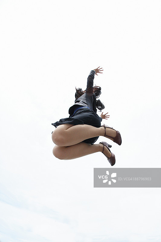 一个女商人在半空中跳跃的低角度视图图片素材