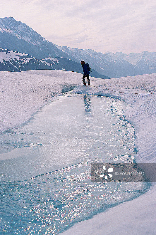 人们在山上穿越结冰的河流图片素材
