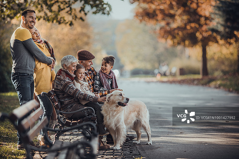 秋日公园里，快乐的多代家庭和他们的狗。图片素材